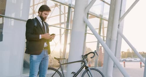 Young Man Uses Mobile Device Next to Bicycle