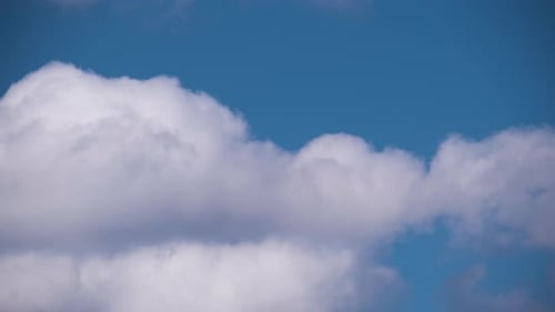 Helle Landschaft aus weißen, geschwollenen Cumuluswolken, die sich unter starkem Wind auf blauem Himmel bilden und verändern