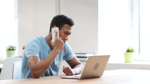 Young Adult Using Smartphone and Laptop Indoors