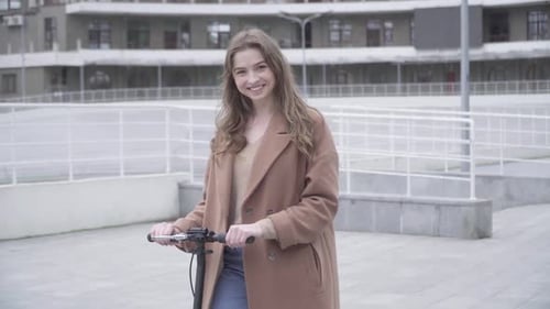 Smiling Woman with Electric Scooter in Urban Setting