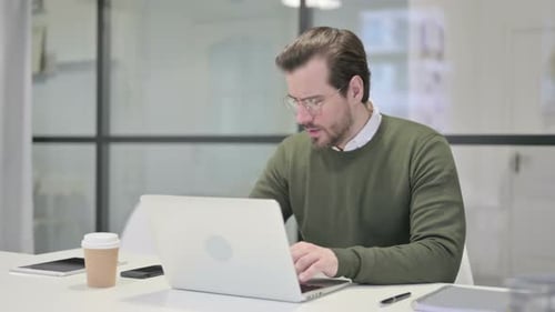 Young Businessman Coughing While Using Laptop in Office