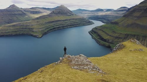 Flying Around a Hiker at the Top of a Mountain Above Funningur on Faroe Islands