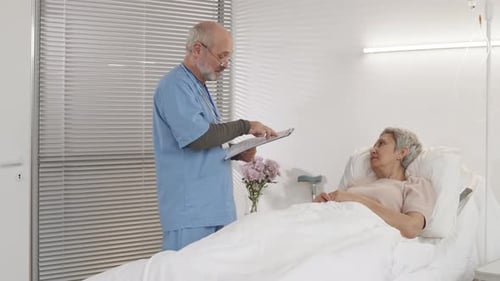 Doctor Consults with Elderly Patient in Hospital Bed