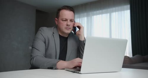 Man Working from Home on Laptop and Phone