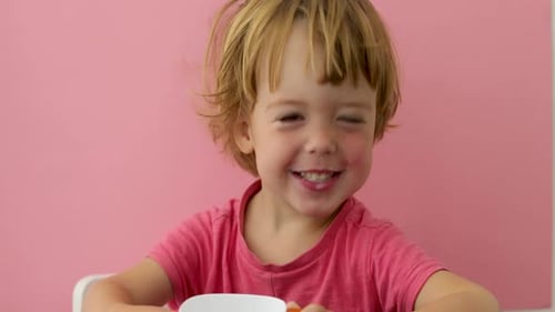 Smiling Child Drinks Milk from Cup