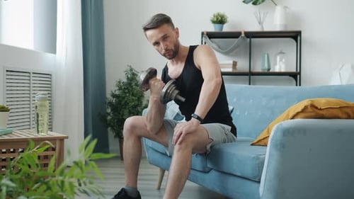 Man Does Dumbbell Curls On Couch At Home
