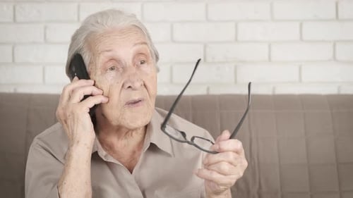 Senior Woman Talking on Phone, Holding Glasses