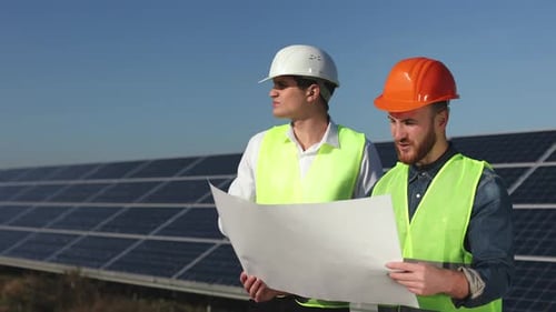 Two Engineers are Standing Next to the Solar Panels