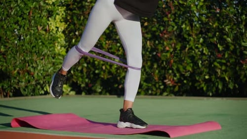 Woman Exercising with Elastic Band on Yoga Mat