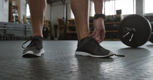 Front view low section of an athletic Caucasian man tying his shoelaces
