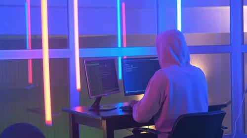 Vue arrière du système de réseau pénétrant Hacker in White Hoodie dans une chambre au néon