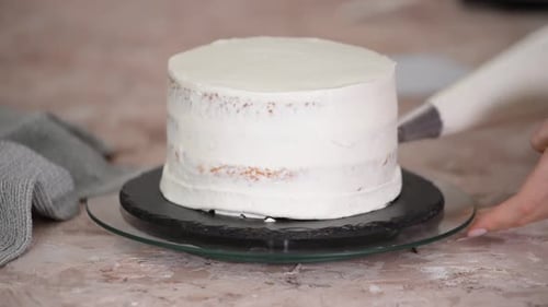 Confectioner squeezing cream on cake at kitchen.