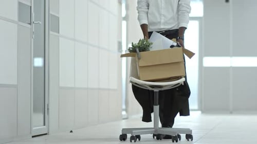 African Businessman Walking with Office Chair and Belongings