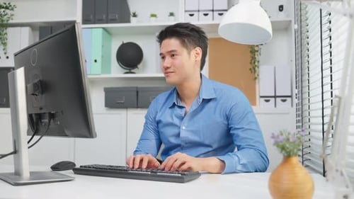 Young Adult Typing at Computer in Office