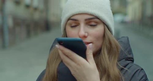 Woman Using Voice Recognition on Smartphone in City