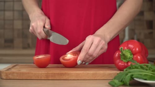 Woman Chopping a Tomato on a Cutting Board