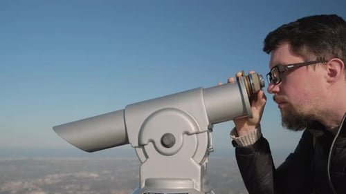 Mann fokussiert Fernglas auf Aussichtsplattform