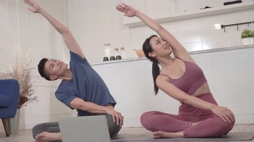 Pareja deportiva asiática viendo un vídeo tutorial para practicar la clase de yoga en casa