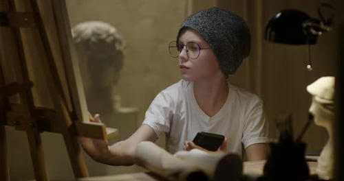 Young Artist Using Phone in Art Studio