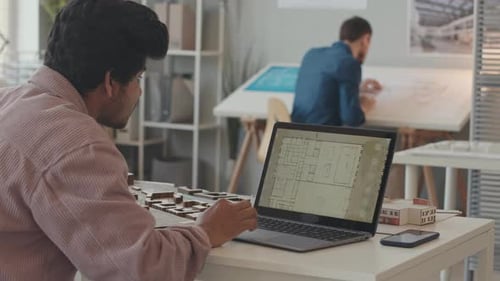 Architects Collaborating on Building Design in Modern Office