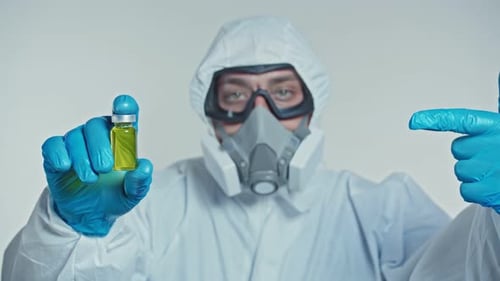 Virologist in a Protective Suit Shows a Developed Vaccine and Thumb Up. Concept of Global Pandemic