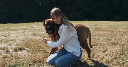 Girl Hugging Her Bullmastiff Dog in Field