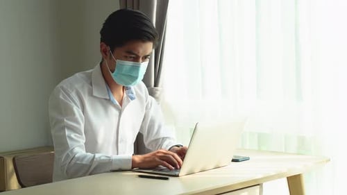Young Adult Working at Laptop Wearing Face Mask
