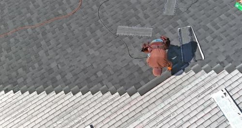 A Asphalt Shingles Installation on the Roof Roofer is Nailing Asphalt Shingles to Roofing