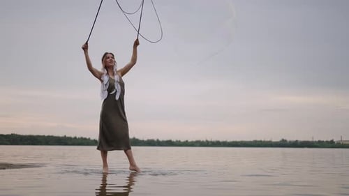 Woman Makes Giant Bubbles at Beach at Sunset