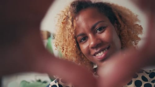 Woman Makes Heart Shape with Hands for Camera