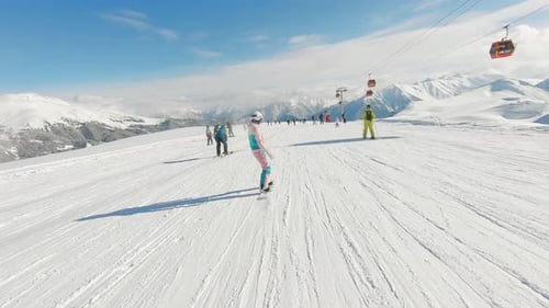 Woman Snowboarder on Snowboard Running Down the Slope in Ski Resort