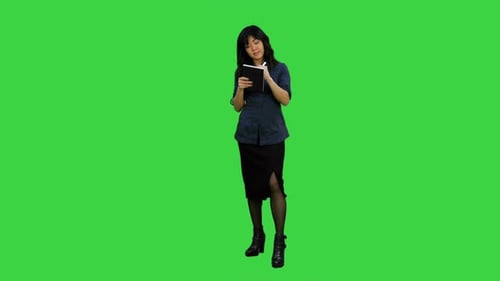 Young Asian Businesswoman Making Notes During Interview on a Green Screen, Chroma Key