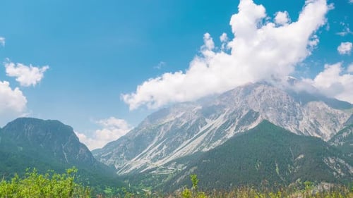 Time lapse: clouds moving against blue sky, sunny day on the Alps, view point over rocky mountain pe