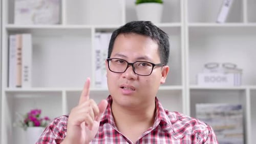 Man Talking and Gesturing in Front of Bookshelf