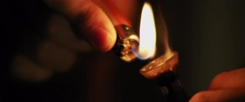 A person lighting up a glass bong of weed, process of smoking medical marijuana