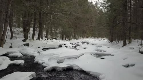 Drohne fliegt im Winter tief über dem verschneiten Fluss