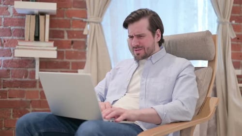 Frustrated Man Using Laptop While Sitting in Chair