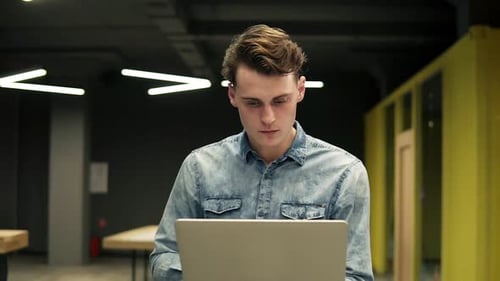Young Man Working on Laptop in Modern Office