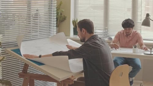 Architect Rolling Out Building Plan on Desk