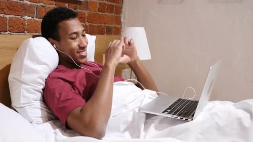 Man Lying in Bed on Laptop Video Call