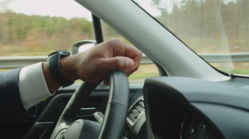 Hand des schwarzen männlichen Fahrers, der das Lenkrad während der Fahrt hält