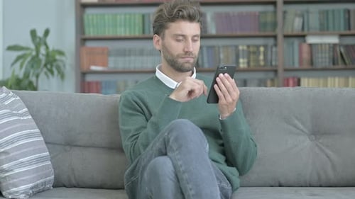 Young Adult Using Phone on Couch Indoors
