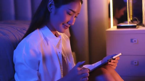 Woman Using Tablet Device in a Lit Bedroom