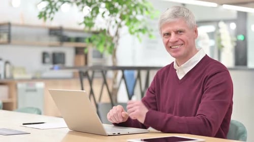 Mature Man Working on Laptop Gives Thumbs Up