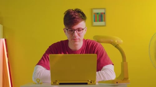 Young Adult Video Conferencing At Yellow Desk