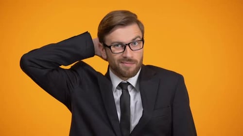Confused Man Poses in a Suit Against Orange