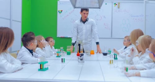 Teacher Explaining an Experiment to a High School Chemistry Class Together