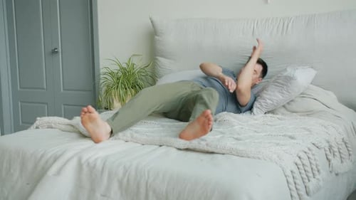 Man Relaxes on Bed in Bright Room