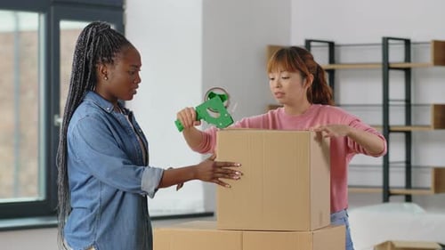 Women with Adhesive Tape Packing Boxes at Home