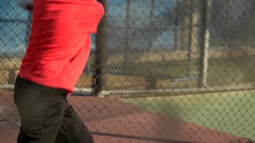 Young Baseball Player Practicing Batting in Cage
